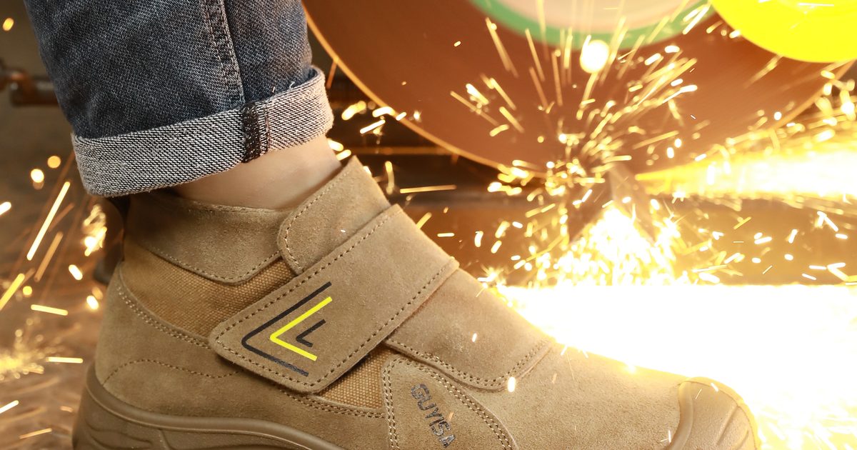Welding-style safety shoe with hook-and-loop flap in a grinding-spark test
